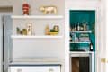 Home bar with teal walls, shelves of liquor bottles, books, and glassware; adjacent wall with decorative shelves.