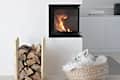 Fireplace with burning logs, wood stack, and a small dog in a woven basket on a light floor.