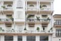 White colonial-style building with balconies, arched windows, and potted plants.