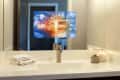 Bathroom sink with folded towels, a lit candle, and a mirror displaying a digital news graphic.
