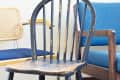 Three chairs: a worn black wooden chair, a blue cushioned chair with wooden arms, and a cane-backed chair.