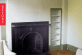 Empty room with a black marble fireplace, built-in shelves, and hardwood floor.