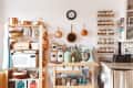 Cozy kitchen with wooden shelves, copper pans, spice jars, a mint green mixer, and a microwave.