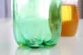 Green plastic bottle trap with liquid inside, next to a jar of honey.