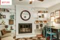 Living room with white brick fireplace, round mirror, teal desk, and built-in shelves with books and decor.