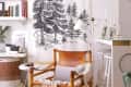 Cozy living area with leather chair, forest tapestry, white lamp, and decorative candles on a bar counter.