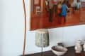 Wooden shelf with decorative vases, a tall sculpture, and a painting of musicians in a room.