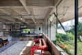 Spacious loft with concrete ceiling, red tufted sofa, large windows, bookshelves, and city view.