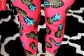Pink leggings with pineapple print paired with turquoise sneakers on a black and white patterned rug.