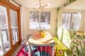Dining room with a wooden table, blue chairs, yellow bench, and tropical wallpaper, overlooking a snowy landscape.