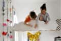 Children playing on a cloud-shaped loft bed in a floral-decorated room.