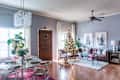 Living room with Christmas tree, brown leather sofa, glass coffee table, and dining area with round table and chairs.
