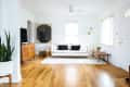 Living room with white sofa, black cushions, wooden floor, mid-century cabinet, and a large target wall art.
