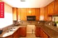 Wooden kitchen cabinets with granite countertops, double sink, and black microwave.