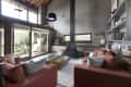 Living room with red sofas, glass coffee table, large windows, telescope, and a black chimney.