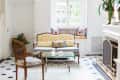Elegant living room with vintage sofa, glass coffee table, patterned cushions, and a fireplace.