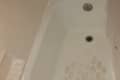 Bathtub with a silver faucet, drain, and soap holder, featuring a textured non-slip surface.