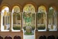 Stone courtyard with arched columns, central well, and climbing vines.