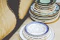 Stacks of vintage decorative plates with floral and ornate patterns on a table.