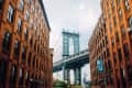 Manhattan Bridge framed by red brick buildings in Dumbo, Brooklyn.