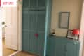 Hallway with teal louvered closet, matching console, red lamp, and framed photo. Open door leads to a bright room.