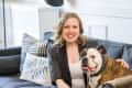 Woman sitting on a gray sofa with a bulldog, next to a pillow with "Haters Gonna Hate" text.
