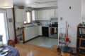 Kitchen with white cabinets, stainless steel stove, cluttered countertops, and cleaning tools on the floor.