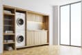 Laundry room with stacked washer and dryer, wooden shelves, folded towels, and a small sink under a window.