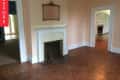 Empty living room with peach walls, white fireplace, ornate mirror, and parquet flooring, labeled "Before."