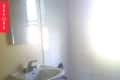 Small bathroom with pedestal sink, toilet, and bathtub, featuring beige walls and tiled floor.