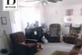 Living room with floral sofa, brown armchairs, ceiling fan, and a small rug, labeled "Before" in the top left corner.