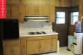 Wood-paneled kitchen with electric stove, oven, and water cooler next to a door and window.