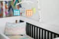 Crib with colorful mobile, patterned pillow, and chevron wall art in a nursery.
