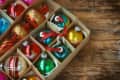 Box of colorful Christmas ornaments on a wooden table.