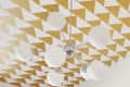 Geometric gold and white triangle ceiling with modern chrome and globe light fixture.