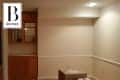 Empty room with beige walls, built-in wooden cabinet, and cardboard boxes on the floor.