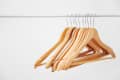 Wooden hangers on a metal rod, neatly arranged in a row.
