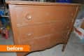 Worn brown wooden dresser with three drawers and large round knobs in a cluttered garage.