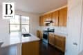 Kitchen with wooden cabinets, white countertops, stainless steel stove, and subway tile backsplash.
