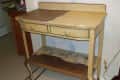 Worn yellow wooden side table with two drawers and a lower shelf, showing signs of distress and peeling paint.