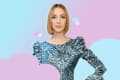 Woman in a blue patterned dress with puffed sleeves, standing against a pastel background with heart shapes.