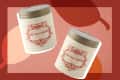 Two Boulangerie Sweet Vanilla Cinnamon candles with ornate red labels on a warm-toned abstract background.