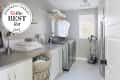 Laundry room with patterned wallpaper, washer, dryer, ironing board, and a basket of towels on a countertop.