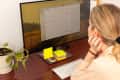 A woman sitting at a computer desk, reviewing a digital calendar app