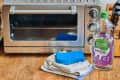 A toaster oven next to cleaning supplies
