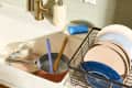 angled shot of a sink full of dishes, with a drying rack full of dishes to the right of the sink.