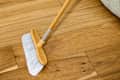 angled shot of someone sweeping up a hardwood floor