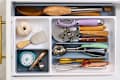Kitchen drawer filled with various utensils including wooden spoons, a timer, measuring cups, and a whisk.