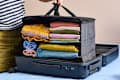 A person packing a suitcase with neatly folded colorful clothes, including a yellow embroidered top and denim.