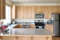 Spacious kitchen with light wood cabinets, granite countertops, stainless steel appliances, and a red rice cooker.